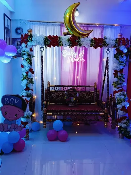 A beautiful home setup for a baby shower, featuring a traditionally decorated swing and floral arch.