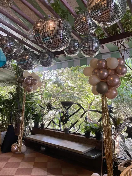 A closer view of the disco ball and balloon columns for the 60th birthday celebration. The mix of metallic and neutral-colored balloons with shimmering tassels creates a fun yet sophisticated party atmosphere.