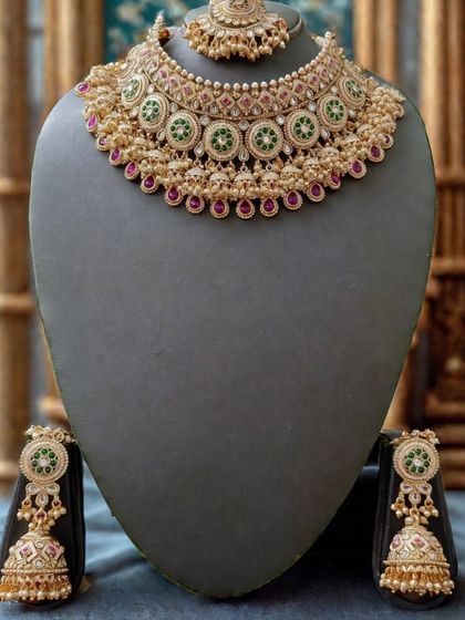 The full view of this classic kundan set, showing the choker, jhumkas, and maang tikka against a dark background to highlight its details.