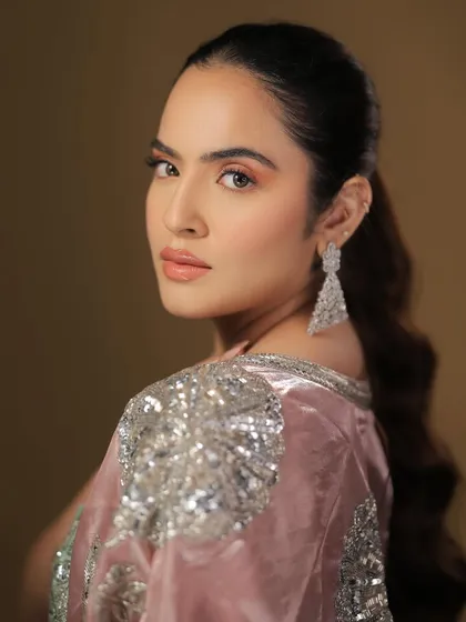 A beautiful over-the-shoulder shot that highlights the long, wavy ponytail and the soft, glowing makeup.