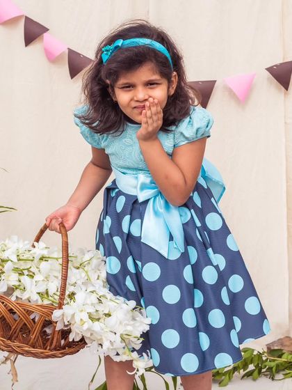 A playful pose in a bold blue polka dot dress. The light blue lace bodice and large satin bow create a fun contrast with the dark blue dotted skirt.