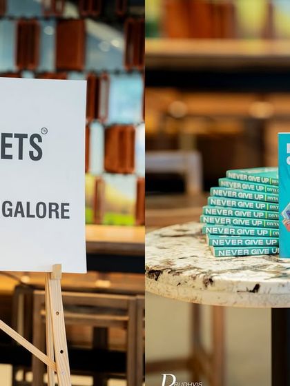A simple, clean setup showing our branding next to a stack of the featured book, "Never Give Up," at a Starbucks cafe.