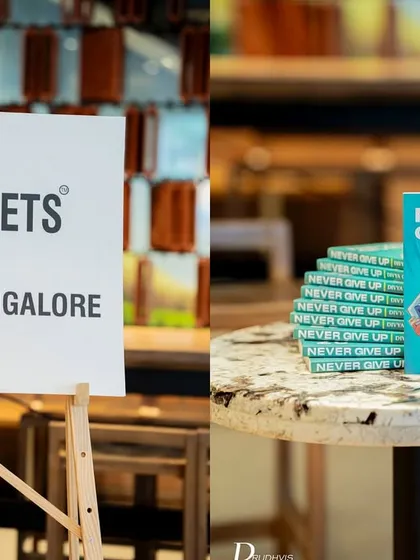 A simple, clean setup showing our branding next to a stack of the featured book, "Never Give Up," at a Starbucks cafe.