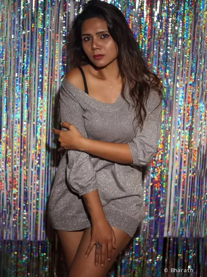 A slightly different pose with the same party-ready look. The lighting catches the glitter of the dress.