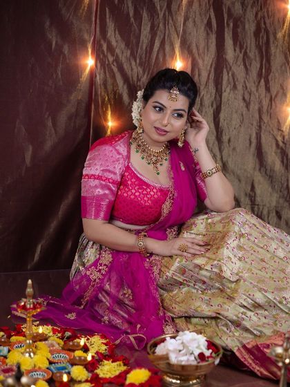 A full-length shot from the festive Diwali photoshoot. The makeup is designed to complement the vibrant pink and gold lehenga, creating a complete, celebratory look.
