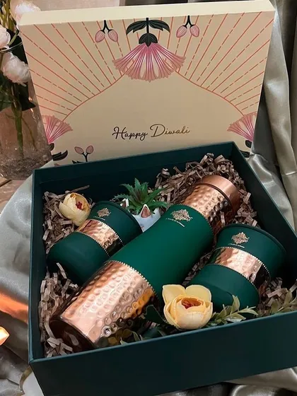 A sophisticated Diwali gift set featuring a hammered copper bottle and matching glasses in a beautiful emerald green gift box.