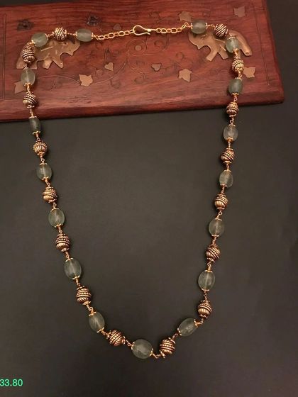 A closer look at the pastel green beaded necklace. The combination of smooth green beads and textured golden beads creates a beautiful contrast.