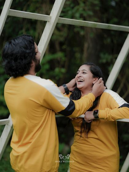 A playful and happy moment between a couple in matching yellow sweatshirts, their laughter captured perfectly.