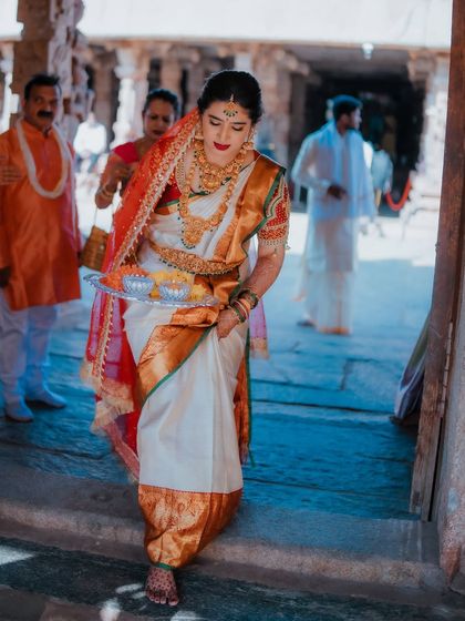 The bride's entrance during a temple wedding ceremony, carrying a traditional tray of offerings. This shot captures her grace and the solemnity of the occasion.