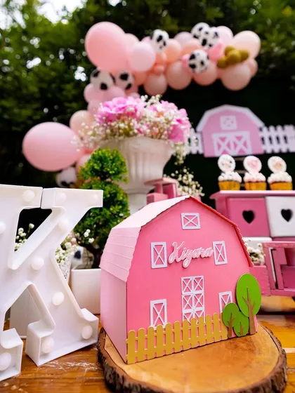 Custom props bring the theme to life. This personalized pink barn and light-up initial 'K' create a beautiful focal point on the dessert table, making the celebration feel truly special and unique.