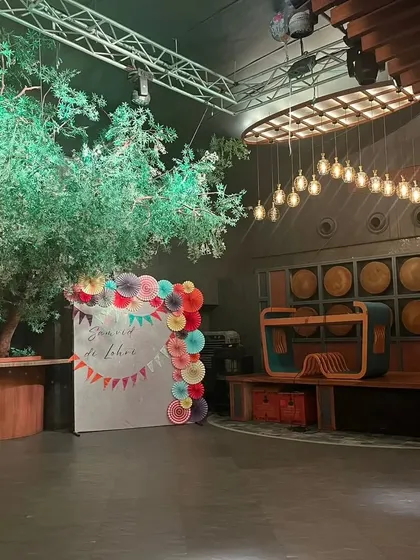 A simple and elegant photo booth for a Lohri celebration. The backdrop is decorated with colorful paper fans and a "Samvid di Lohri" message.