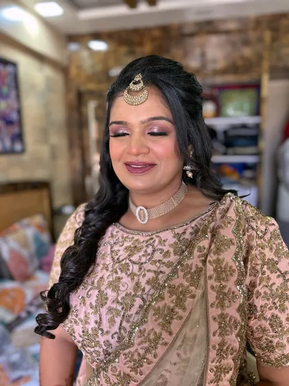 A beautiful client ready for her event. The makeup features a soft pink smokey eye and a matching lip, complemented by a maang tikka.