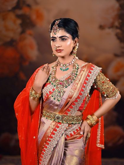 A full-body shot of a model in a beautiful bridal saree, showing the complete look from head to toe. The floral backdrop adds a touch of softness and romance.