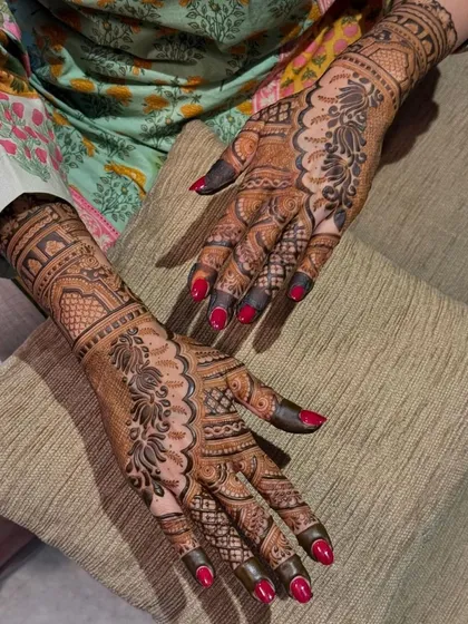 A beautiful floral and paisley design with a rich, dark stain. The red nail polish provides a stunning contrast, making the henna art pop.