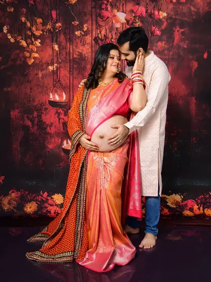 We love capturing the beauty of tradition. This couple's maternity portrait, set against a rich, warm backdrop with hanging lamps, highlights their connection and the elegance of a traditional saree, complete with intricate jewelry and henna.
