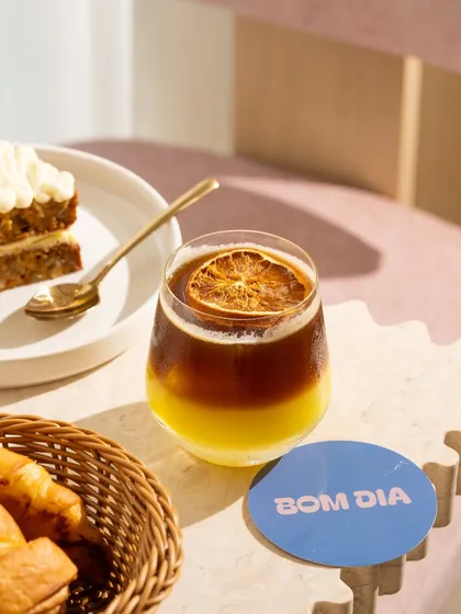 An iced coffee and carrot cake from Bom Dia, with the branded coaster clearly visible.