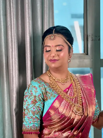 A beautiful portrait of a bride on her wedding day. Her hair is in a classic updo, adorned with a matha patti, showcasing a timeless and elegant bridal style.