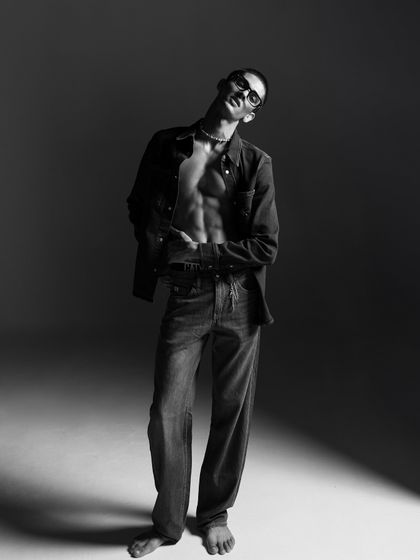 A dynamic full-length pose in black and white. The lighting creates a dramatic silhouette, showcasing the entire outfit while maintaining an artistic, editorial feel.