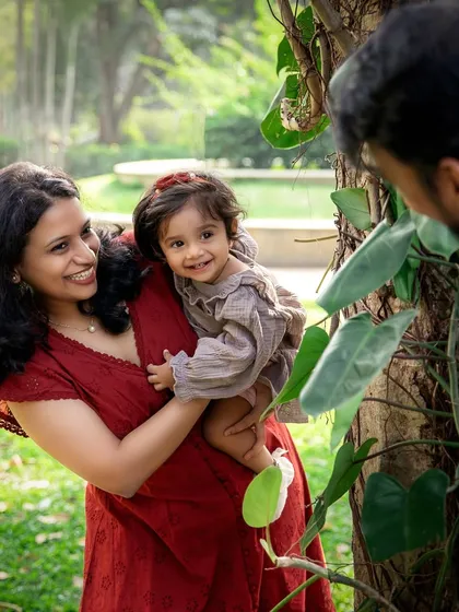 A playful moment during an outdoor family photoshoot. Using the natural environment, like this tree, adds a fun and interactive element to the session.