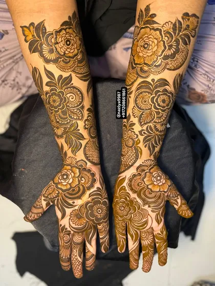 Both hands adorned with matching, intricate floral patterns. This design covers the hands and extends just past the wrist, perfect for a sangeet or wedding reception.