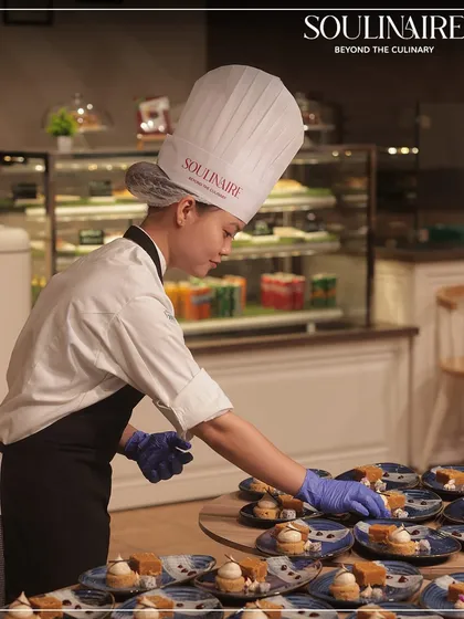 A female chef meticulously plating desserts, showcasing the precision and care that goes into every single dish we serve.