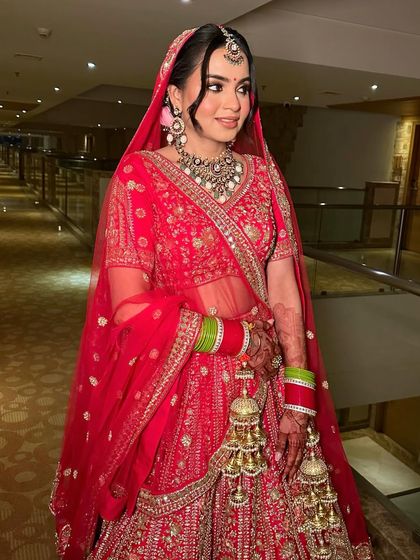 The full look of this stunning bride in her red lehenga. The makeup is classic and elegant, with a focus on radiant skin and defined eyes.