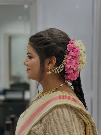 A side profile of this elegant bridal look, highlighting the intricate hairstyle with fresh flowers, a skill we teach alongside makeup application.
