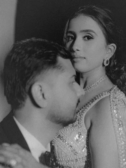 A soft, intimate black and white portrait, capturing a quiet moment of affection between the couple amidst the Sangeet festivities.