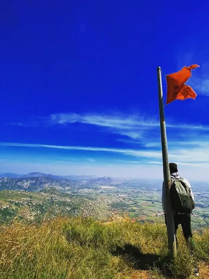 Standing by the flag at the peak of Skandagiri, looking out over the Chikballapur landscape. This is a classic and rewarding South Indian trek.