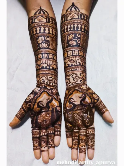 This intricate bridal henna showcases a blend of auspicious symbols. You can see graceful peacocks on the palms and the sacred swastika symbol on the forearms, all woven together with detailed filler patterns.