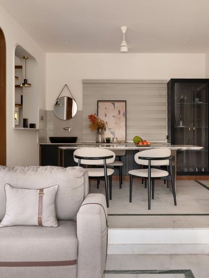 A view of the elevated dining area, designed with a custom marble-top table and gracefully curved chairs. The space feels open yet distinct, perfect for family meals.