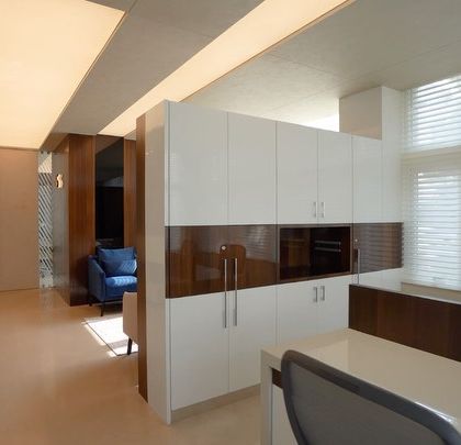 A section of the office featuring semi-private workstations and glossy white storage cabinets. The design uses partitions and built-in furniture to create defined work zones without sacrificing the open feel of the office interior.