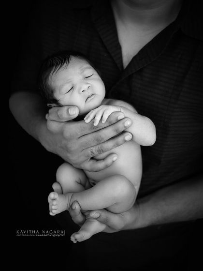A father's strong arms securely hold his nine-day-old newborn. This classic black and white portrait is one of my favorites for its timeless depiction of paternal love.