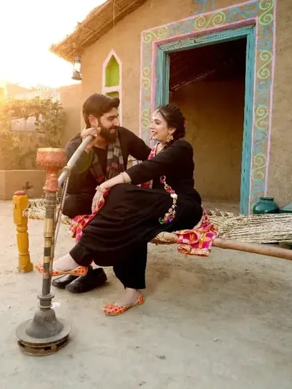 Your pre-wedding shoot can reflect your roots and personality. This couple wanted a rustic, traditional Punjabi village theme, and we created a warm, authentic setting with a charpai and hookah for a truly personal photoshoot.