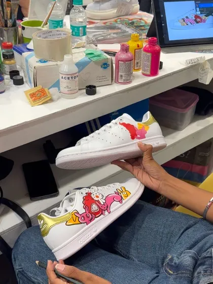 Here I am, bringing a digital design to life on a pair of Adidas Stan Smiths during a live customization event. You can see my iPad with the digital mockup right next to the actual hand-painted work.