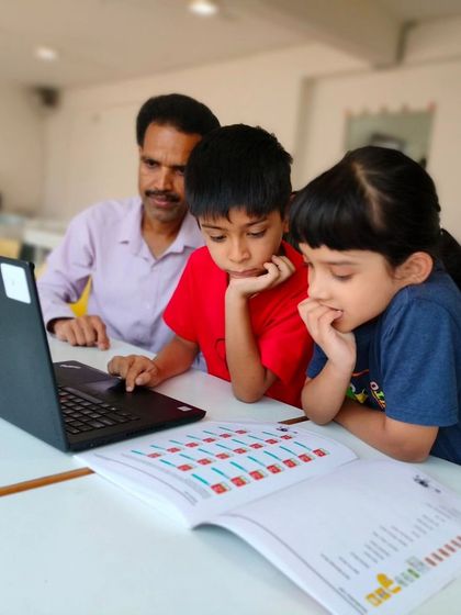 An instructor and two students look at a laptop together, working through a coding problem as a team.