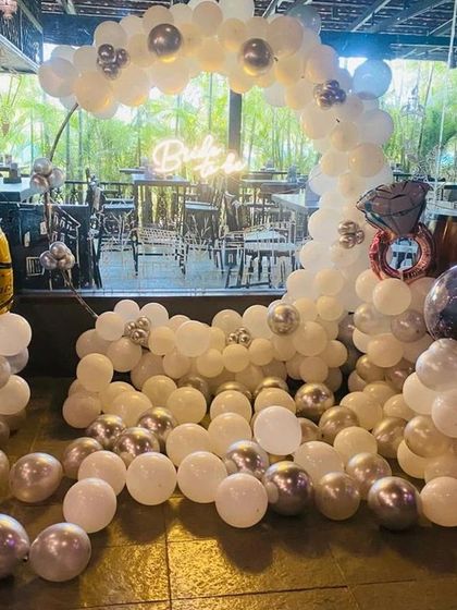 An elegant 'Bride to be' decoration in a restaurant setting. The white and silver balloon arch, complete with champagne and ring foil balloons, creates a sophisticated celebratory atmosphere.