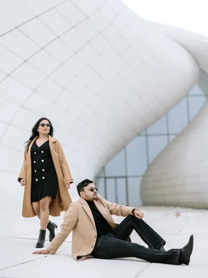 A high-fashion, editorial-style shot in front of the Heydar Aliyev Center in Baku. The minimalist white architecture and the couple's chic, coordinated outfits create a sophisticated and modern look.