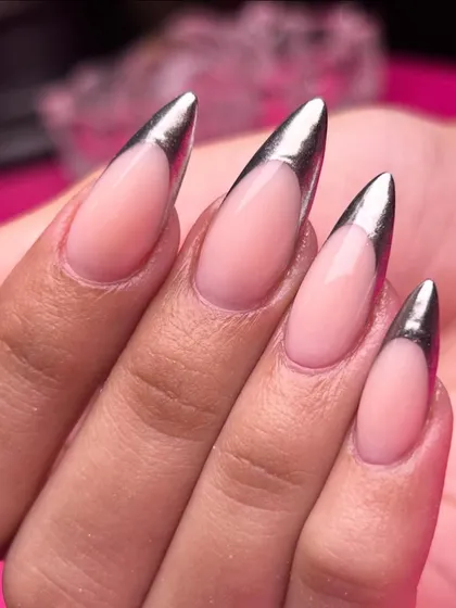 A modern classic with a high-fashion twist. This sharp, stiletto French manicure is elevated with a liquid-metal chrome finish, proving that elegance can also be edgy and bold.