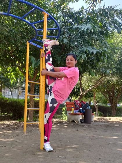 A standing split variation using a pole at the park for support. This is an intense hamstring and hip flexor stretch that demonstrates advanced flexibility.
