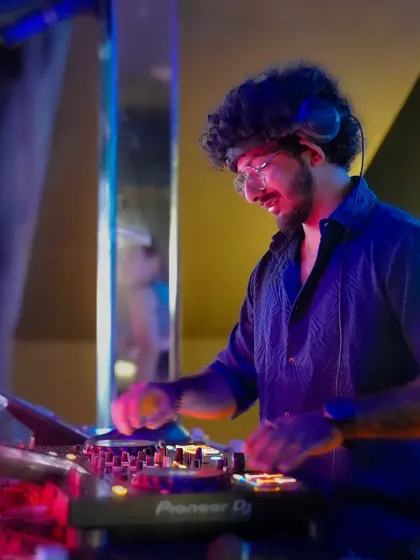 In the zone, mixing tracks under the cool blue lights of the club. My focus is on delivering a seamless set, blending Bollywood, EDM, and commercial hits to keep the dance floor moving.