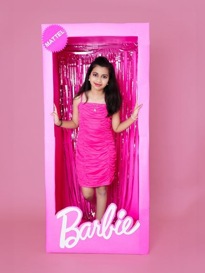 Ready for her close-up! A girl poses confidently inside a life-sized Barbie box prop during her themed birthday photoshoot.