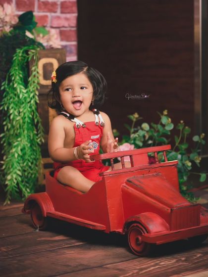 A joyful expression captured as this little girl plays in her red toy car. These action shots are perfect for showing a toddler's happy and energetic personality.
