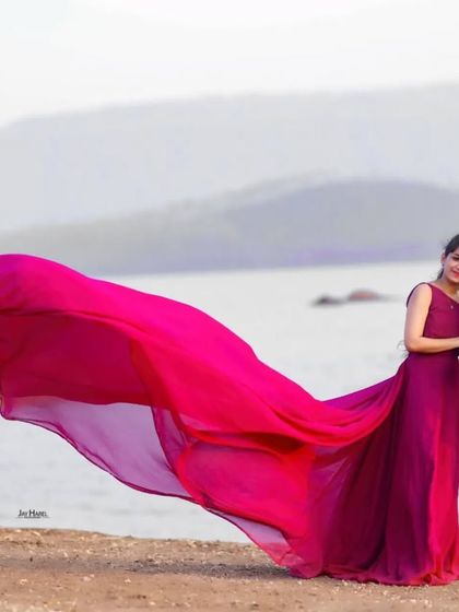 This rich jamun-colored gown with a long, flowing tail is a unique and elegant choice for a pre-wedding shoot by the water.