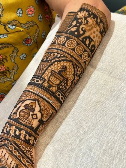 A forearm design composed of multiple traditional bands, featuring pots, birds, and elephants.