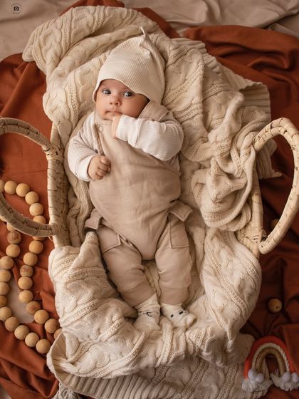 A baby boy in neutral tones looks curiously at the camera from his cozy basket. A perfect example of my simple and soulful style.