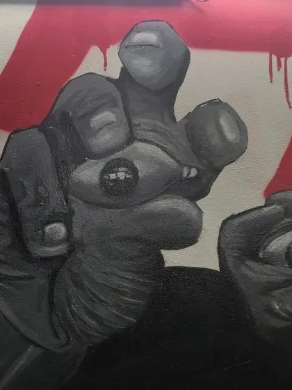 A detail from the mural, focusing on the hands and the eye. This part of the composition adds a surreal, symbolic layer to the portraits.
