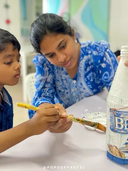 A close-up of the mother-son team working on their beach-themed decoupage bottle.