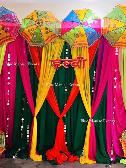 A colorful Haldi backdrop with multi-colored drapes and traditional umbrellas, creating a festive and vibrant look.