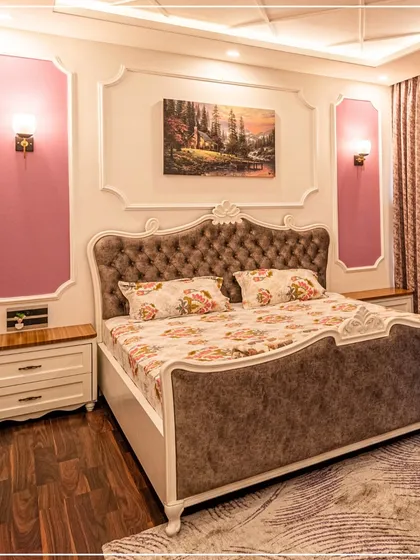 A dreamy bedroom with misty rose walls, a classic tufted headboard, and elegant floral bedding.